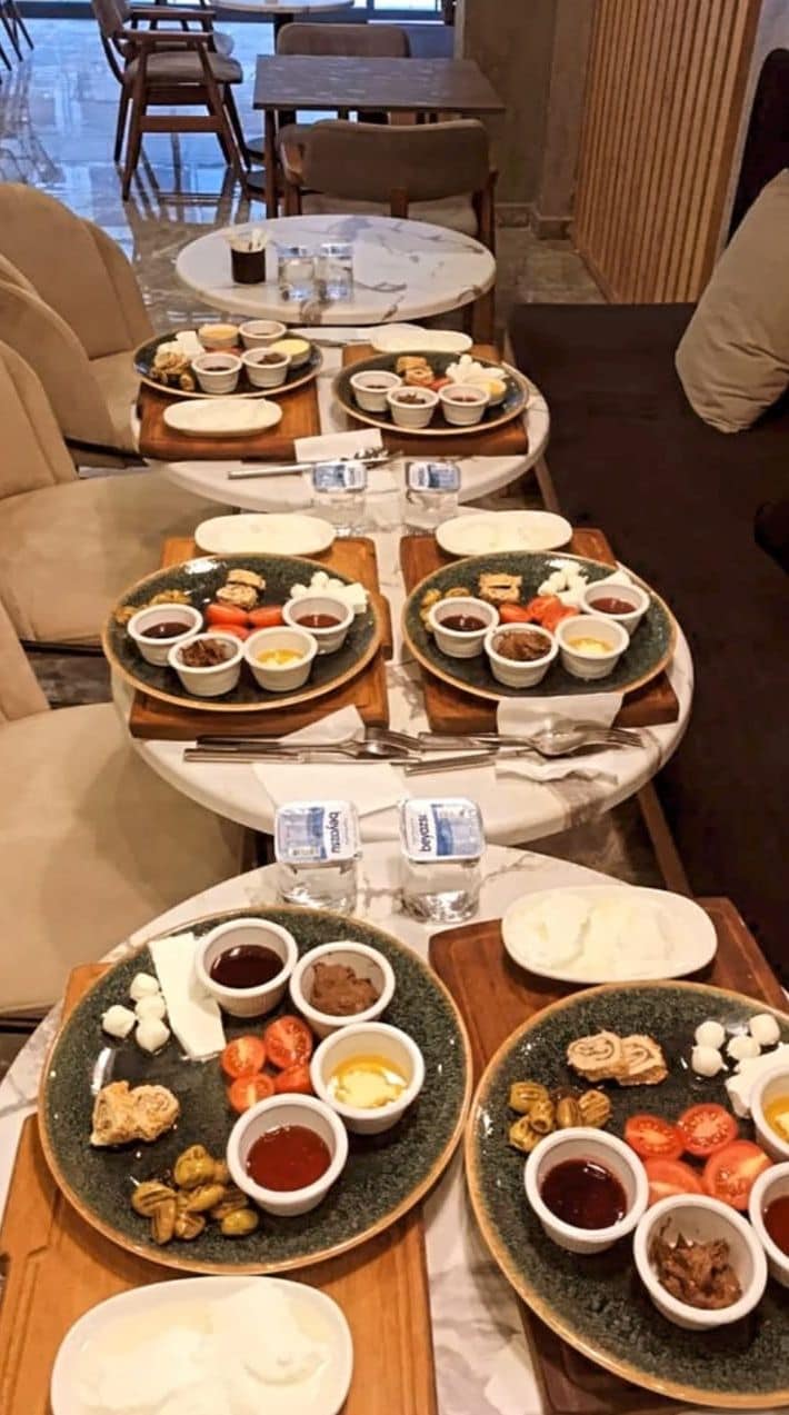 A dining area with round tables, each set with plates of food, bowls of sauces, and condiments.