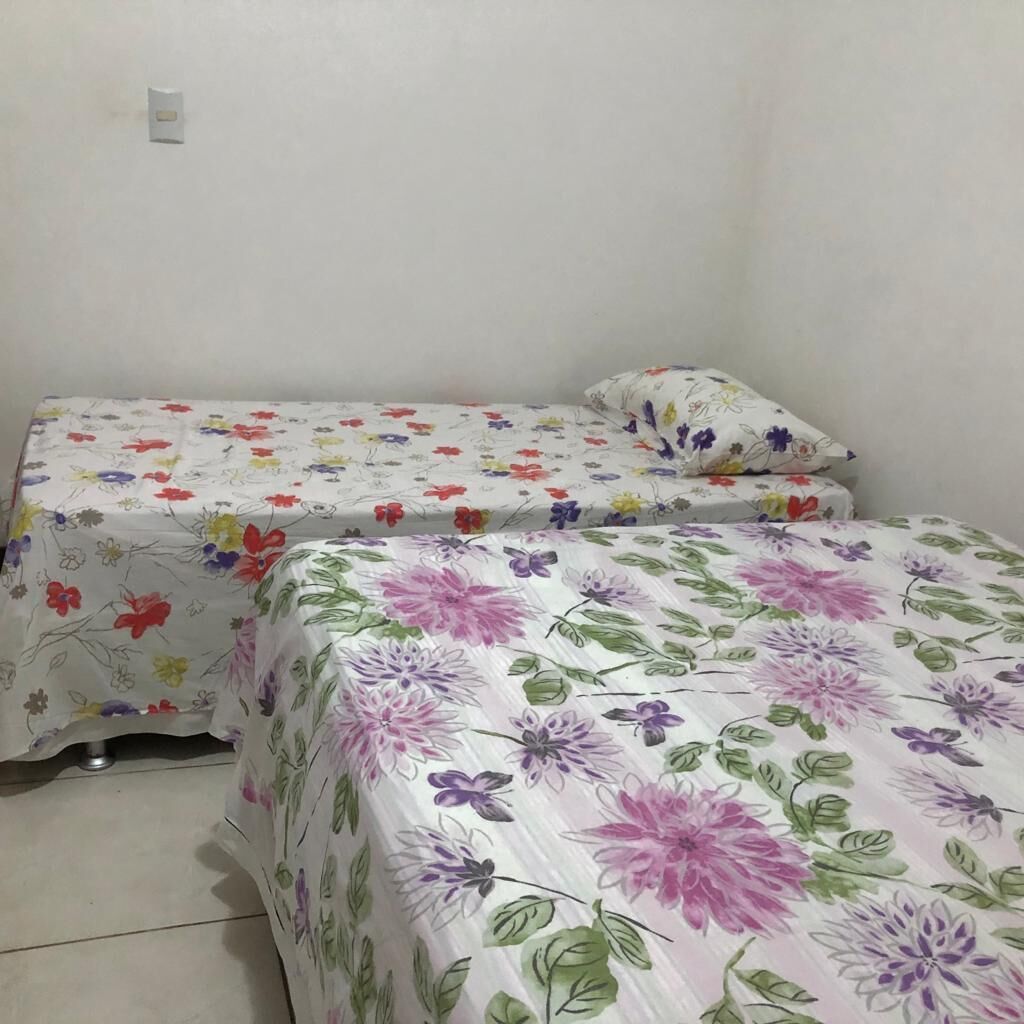 A small room with two beds, each covered with floral-patterned bedding.