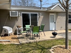 A house with a patio area featuring a table and chairs, a grill, and a covered outdoor seating area.
