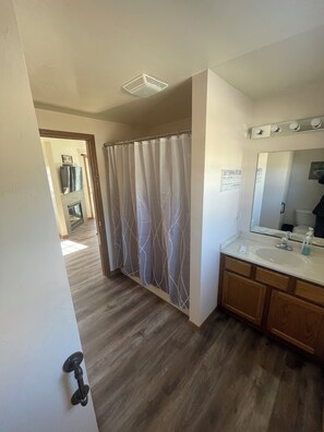 A bathroom with a shower curtain, a sink, and a mirror.