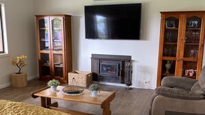 Una sala de estar con chimenea, un televisor montado en la pared y un sofá.