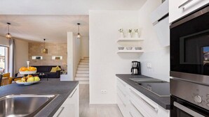 Een moderne keuken met een centraal eiland, een ingebouwde oven en roestvrijstalen apparatuur.