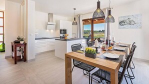 Een moderne keuken met witte kasten, een centraal eiland en hanglampen.
