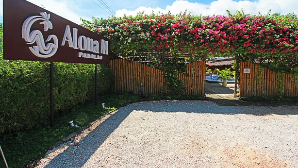 Señal para Alona M. con una valla de madera y plantas con flores.