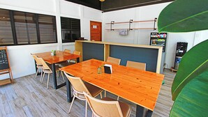 Un salón de conferencias con una mesa de madera, sillas, una pizarra y un expendedor.