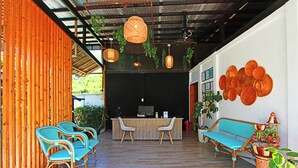 Un área de recepción con un escritorio de madera, dos sillas, un sofá y decoración en la pared.