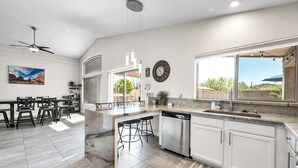 Una cocina moderna con armarios blancos, lavavajillas integrado y una isla grande con taburetes de bar.