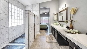 Un baño moderno con cabina de ducha, un espejo grande y tocador con lavabo.