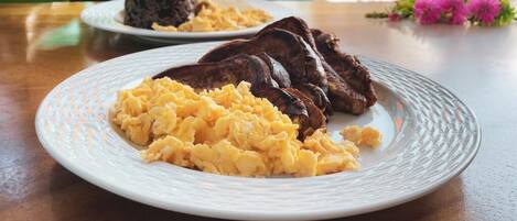 A plate of scrambled eggs and steak on a wooden table.