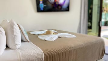 Una cama bien hecha con una colcha color beige, almohadas blancas y un pequeño adorno sobre ella.