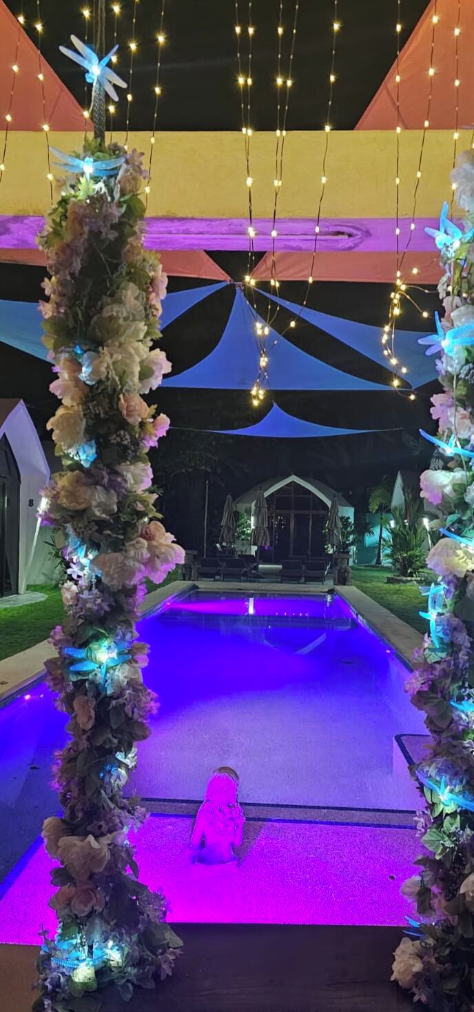 Un área de piscina con un arco decorativo y luces colgantes.