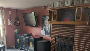 Una habitación con una cama grande, televisión, guitarra, un globo terráqueo y chimenea de ladrillo.