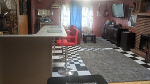Una sala de estar con suelo a cuadros, un sofá rojo, un televisor y una chimenea.