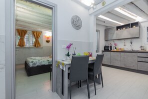 A compact living space with a dining area, kitchenette, and a small bedroom with curtains.