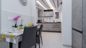 Eine moderne Küche mit grauen Schränken, einem Esstisch mit Stühlen und einer dekorativen Platte an der Wand.