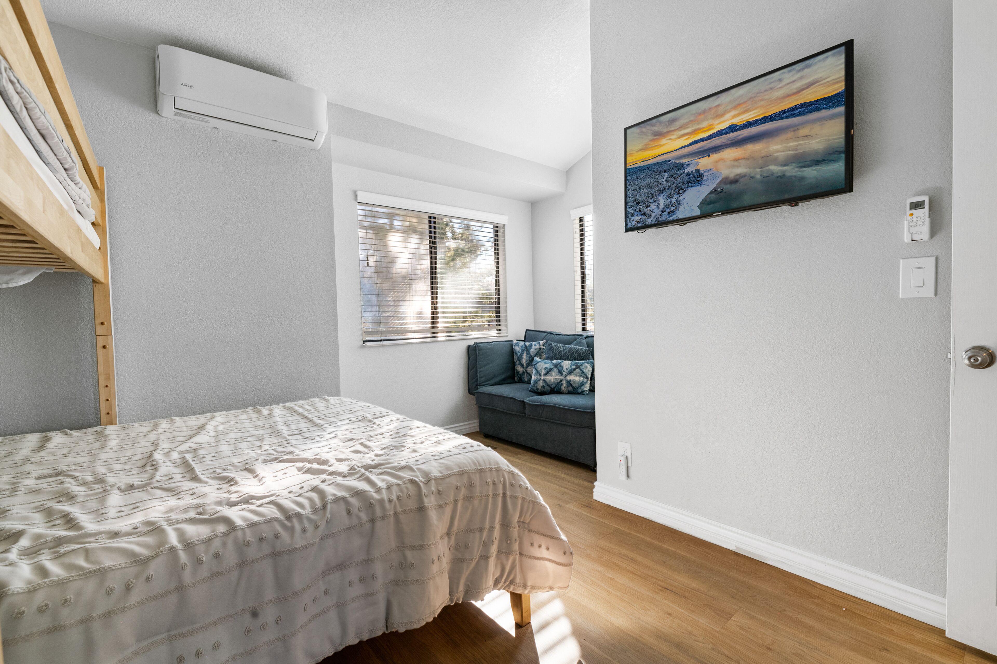 Une chambre à coucher avec un lit, une fenêtre, un canapé et un tableau au mur.