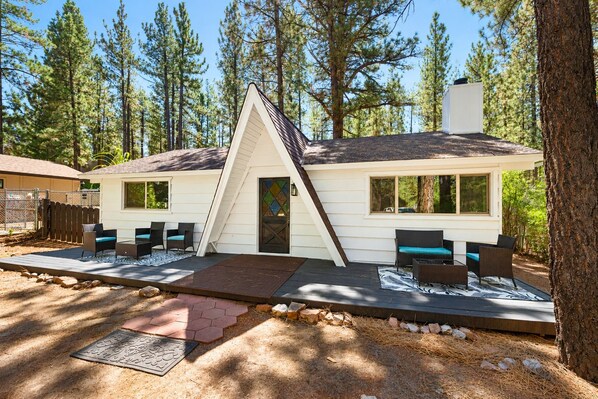 A cabin with a sloped roof, a front porch with seating, and a view of the surrounding forest.