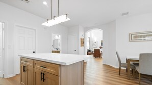 A modern kitchen with wooden cabinets, a white countertop, and a pendant light.