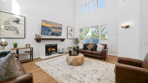 A spacious living room with a fireplace, a large window, and a cozy seating area.
