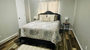 Una camera da letto con un letto, due abat-jour, una porta e una finestra con tende.