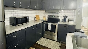 Una cucina moderna con mobili scuri, un forno a microonde, un forno e un tostapane.