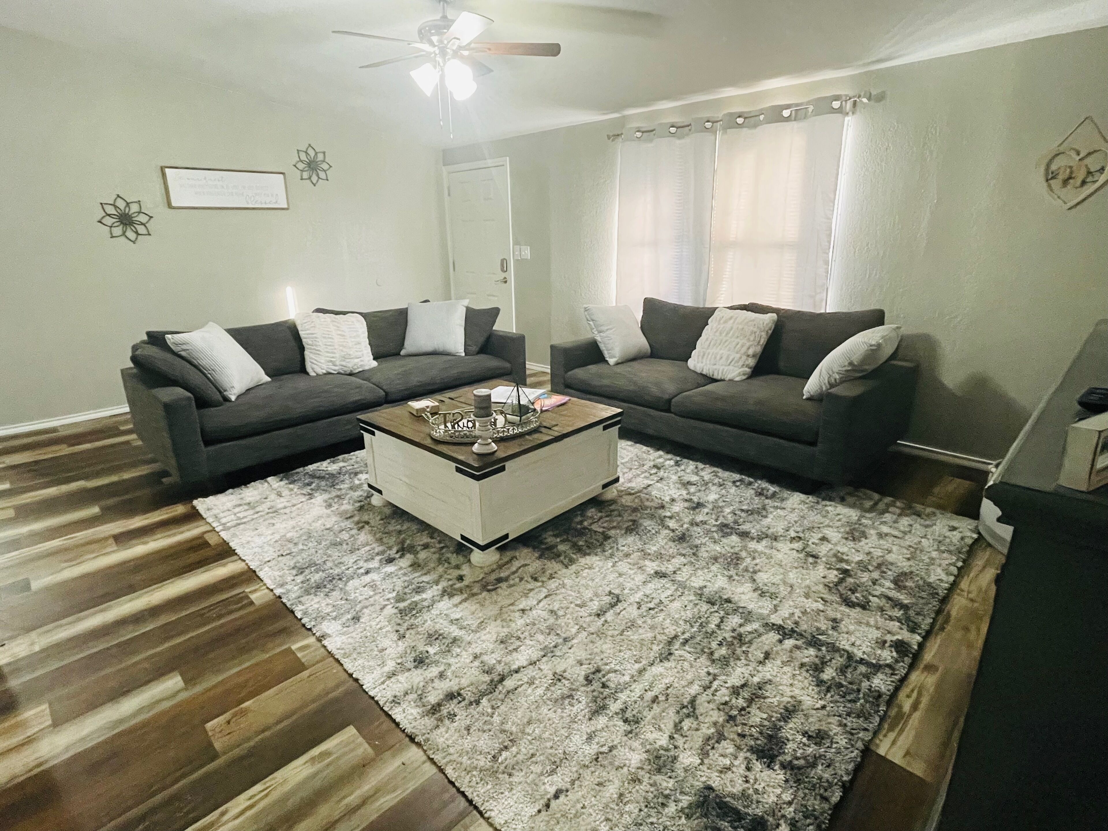 Ein Wohnzimmer mit zwei dunkelgrauen Sofas, einem weißen Couchtisch und einem gemusterten Teppich.
