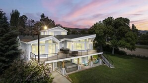 A two-story house with a balcony, a covered patio, and a well-maintained lawn.