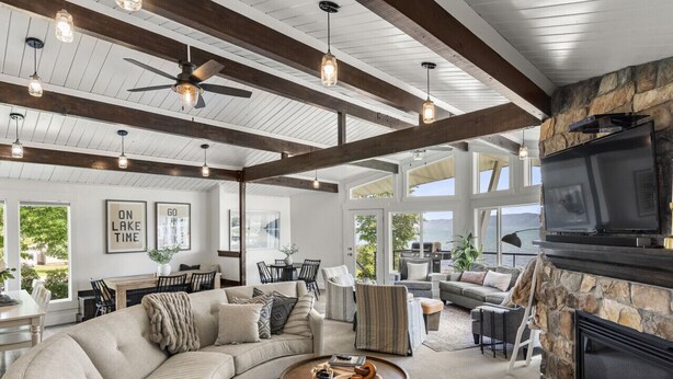 A spacious living room with a stone fireplace, a large sofa, and a ceiling fan.