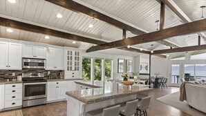 A spacious kitchen with white cabinets, stainless steel appliances, and a large island with bar stools.