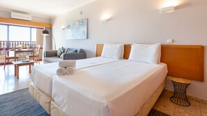 Ein Hotelzimmer mit einem großen Bett, einem kleinen Tisch, einer Couch und einem Balkon mit Tisch und Stühlen.