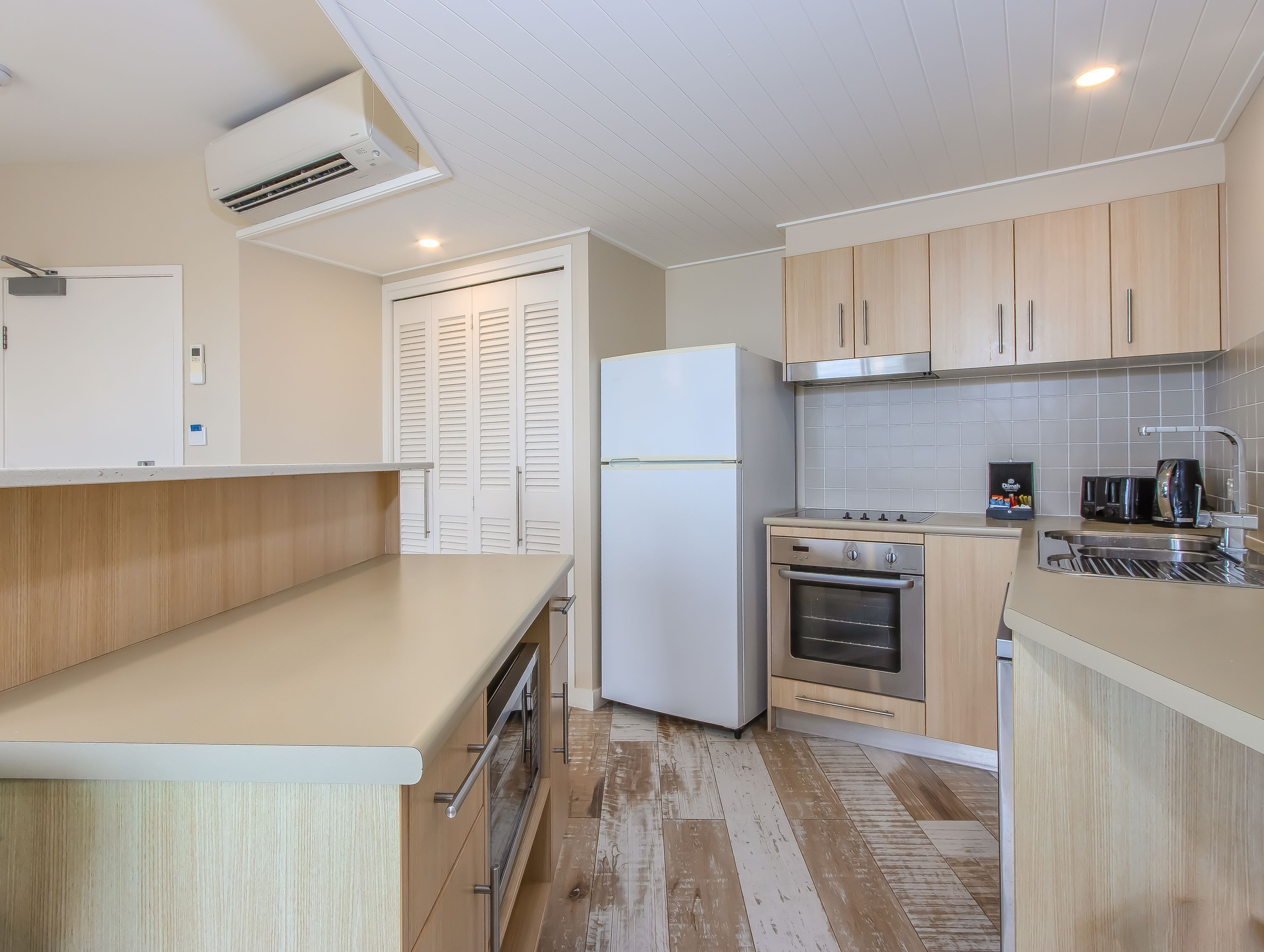 A modern kitchen with wooden cabinets, a white refrigerator, a stove, and a coffee maker.