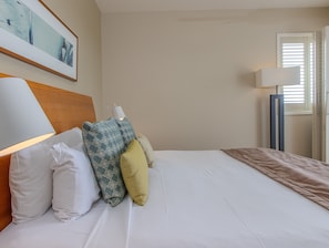A neatly made bed with pillows, a headboard, a bedside lamp, and a framed picture on the wall. - The Pool Resort Kingscliff - 2B Ocean View (2320/21) - Holiday Management Co. (Tweed)