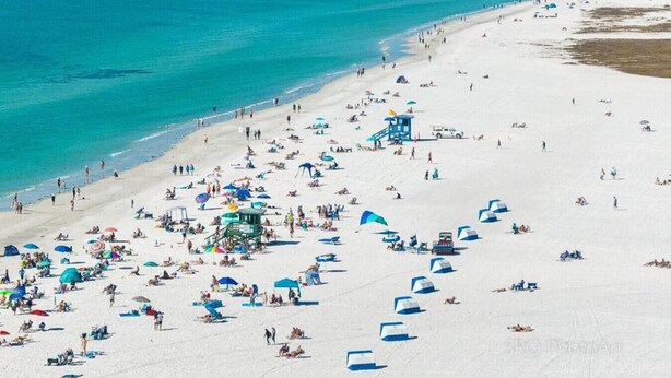 Ein Strand mit vielen Sonnenschirmen und Menschen.