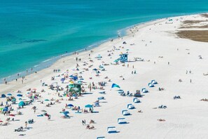 A beach with numerous umbrellas and people.