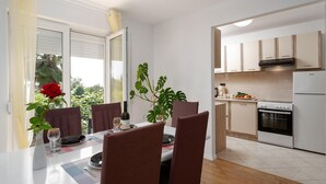 Eine moderne Küche mit weißen Schränken, einem eingebauten Backofen und einem Essbereich mit Tisch für zwei Personen.