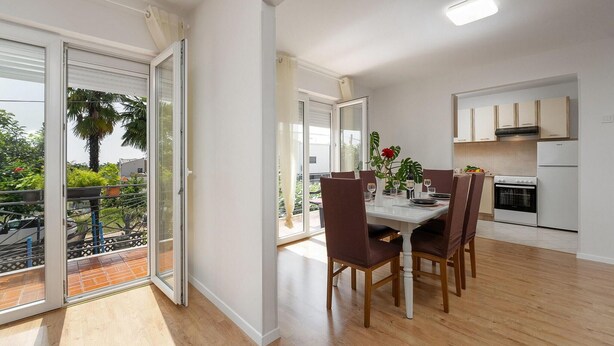 Eine moderne Wohnung mit Essbereich, Küche und Glastüren zum Balkon.