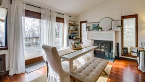 Un salon chaleureux avec une cheminée, un plancher en bois et un coin repas comprenant une table et des chaises.