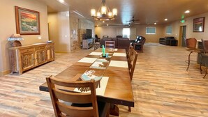 A spacious dining area with a long wooden table, chairs, and a chandelier. There is a television and seating area in the background. - Brand New House Right on Allen St one Block from the Birdcage
 (Tombstone)