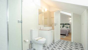 A compact bathroom with a toilet, sink, and shower.