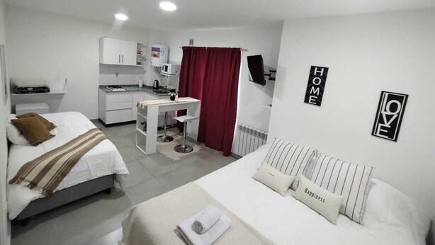 Pieni hotellihuone, jossa on sänky, pieni työpöytä, minikeittiö ja kylpyhuone.
