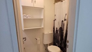 Pieni, käytännöllinen kylpyhuone, jossa on wc, pesuallas ja suihkutila.