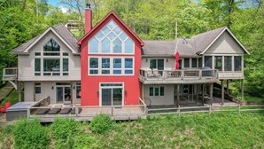 A two-story house with a red front, large windows, and a balcony.