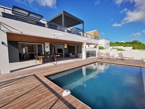 A modern house with a pool, outdoor seating, and a covered patio area. - On the beach, modern villa, swimming pool, panoramic sea view , tropical garden (Saint-François)