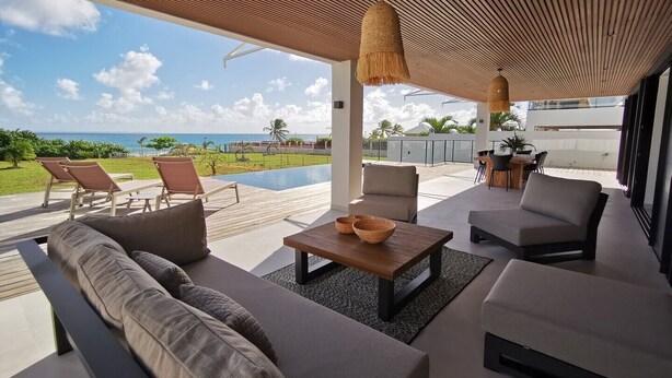 Ein moderner Außenbereich mit Pool, Sitzgelegenheiten und Blick aufs Meer.