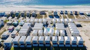 Ett hotell vid stranden med flera våningar, en swimmingpool och en väg som leder ner till stranden.