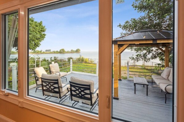 A deck with outdoor furniture, a pergola, and a view of a lake.