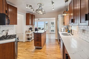 A modern kitchen with wooden cabinets, a marble countertop, and a central island. - Lakefront Retreat - Serene escape on Lake Erie! Amazing Views! Lorain OH (Lorain)