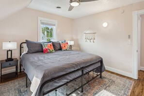 A bedroom with a bed, nightstands, a ceiling fan, a window, a wall-mounted light, and a door. - Lakefront Retreat - Serene escape on Lake Erie! Amazing Views! Lorain OH (Lorain)