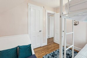 A bedroom with a bunk bed, a door leading to another room, and a blue rug on the floor. - Lakefront Retreat - Serene escape on Lake Erie! Amazing Views! Lorain OH (Lorain)