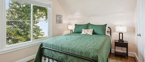 Un dormitorio con una cama, dos mesitas de noche, una ventana y un ventilador de techo.